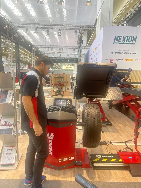 Revisión de una balanceadora de ruedas en el stand de un fabricante durante una feria internacional del sector.